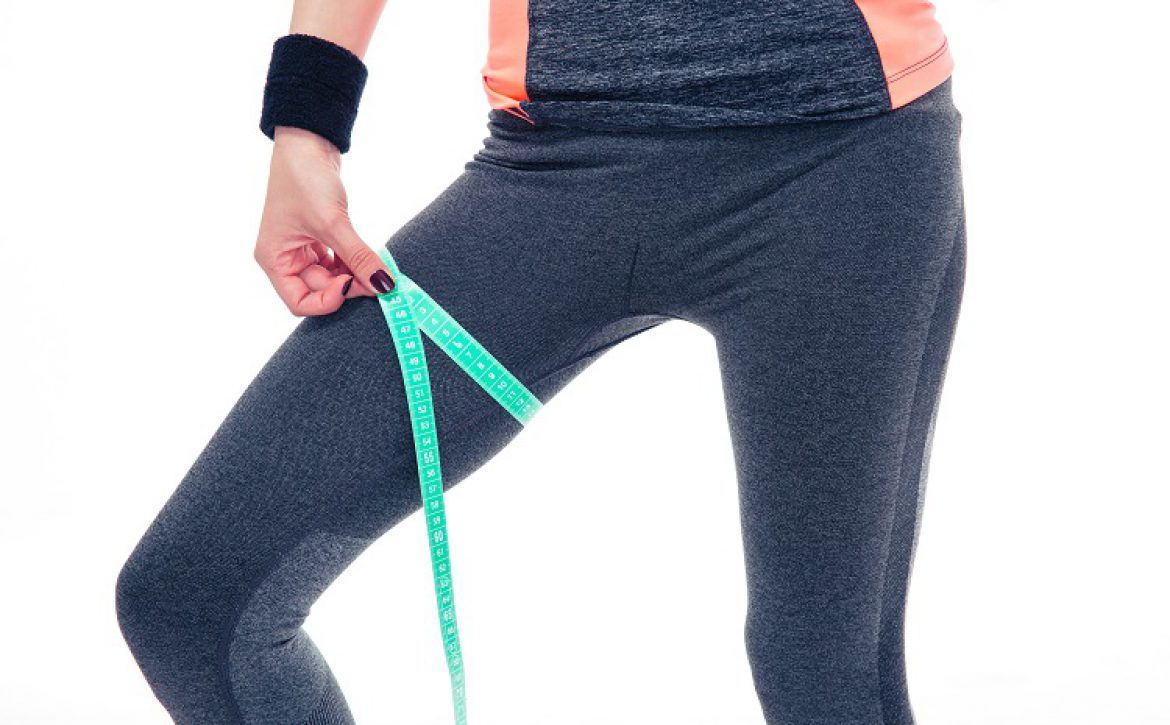 Woman measuring her thigh circumference with tape