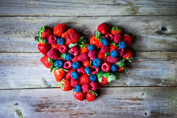 Heart of berries on wooden background